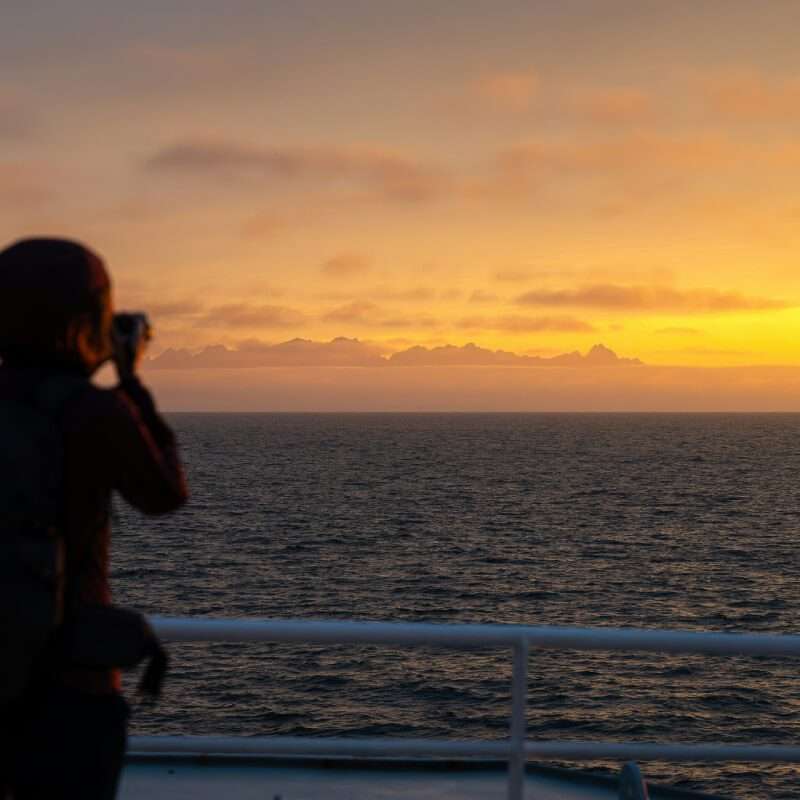 Man taking a photo of the sunset in a boat