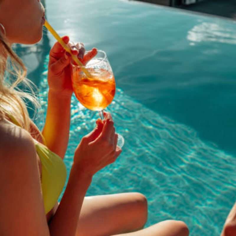Woman lounging by the poolside with a summery drink in hand