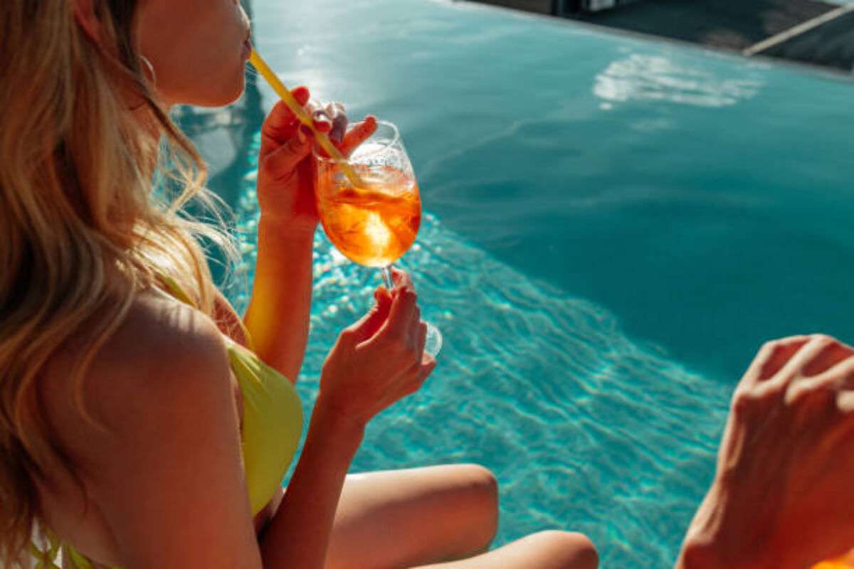 Woman lounging by the poolside with a summery drink in hand